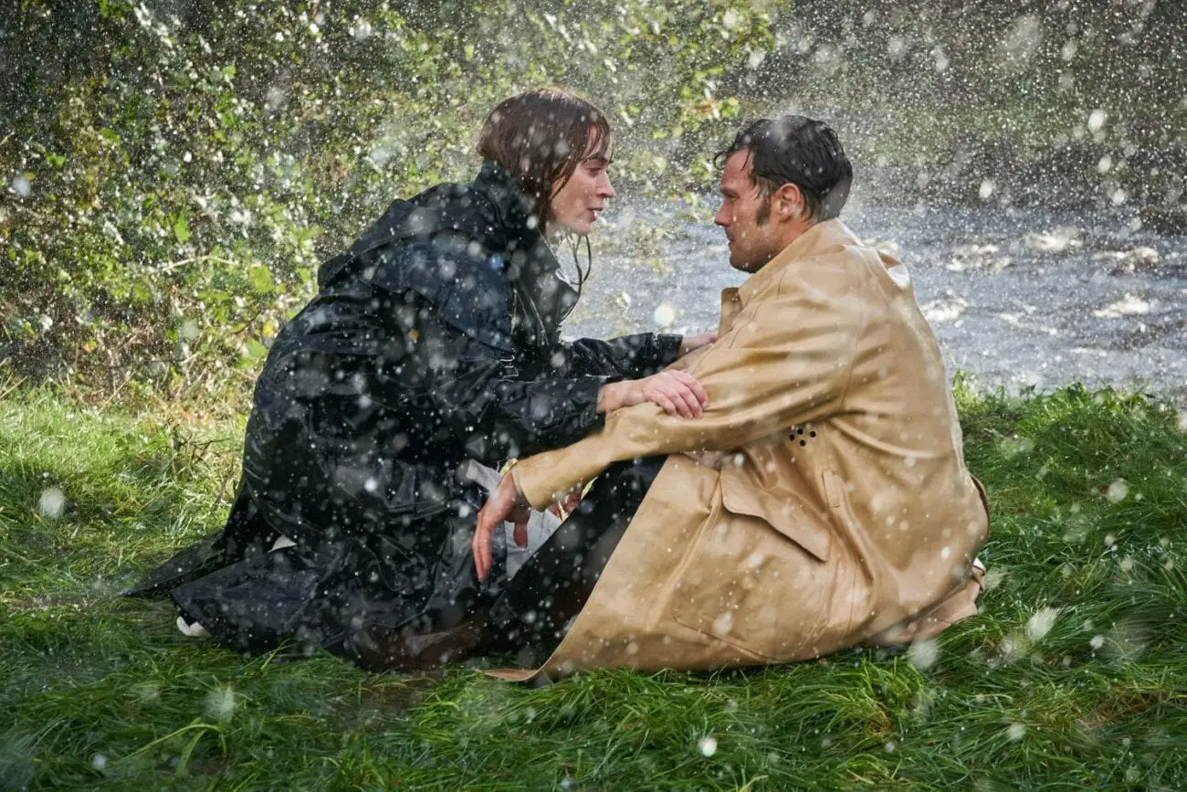 Rosemary and Anthony talk while kneeling and seated in the rain.