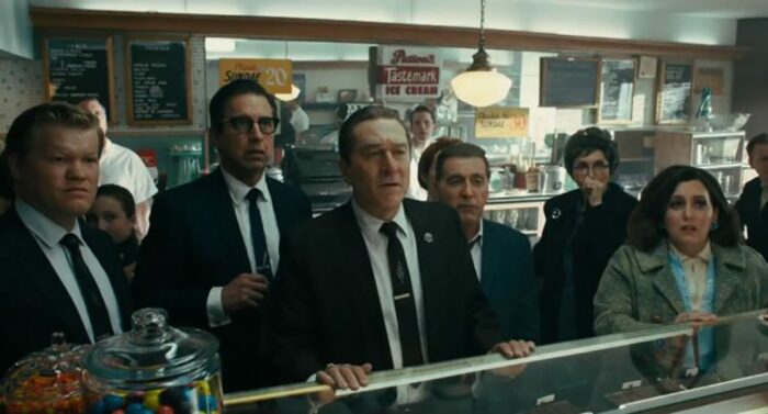A group of people stand in front of a diner and watch a television