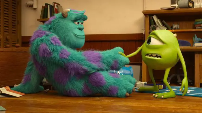 Monsters University characters Sully (left) and Mike (right) in Mike's dorm room. Sully is sitting on the floor, looking at Mike with a confident expression as they shake hands. Mike looks weary. There are several books and other supplies strewn about the room.