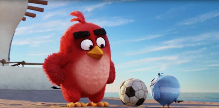 Red standing outside his house (barely visible as it's off to the side) staring down at a tiny, round blue bird who is playing with a soccer ball. Red's hands are on his hips and he looks smug, as he is about to punt the small fella into the sea.