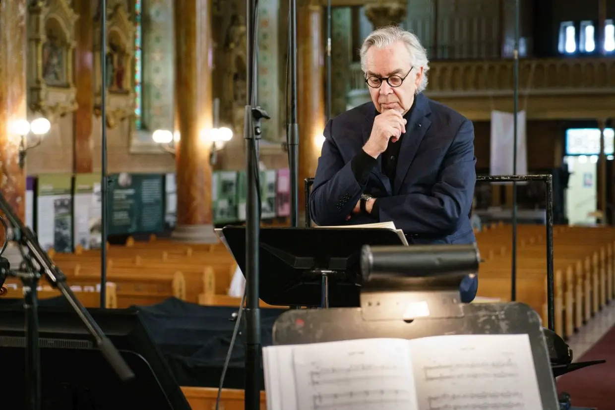Howard Shore stands at a podium overlooking sheet music