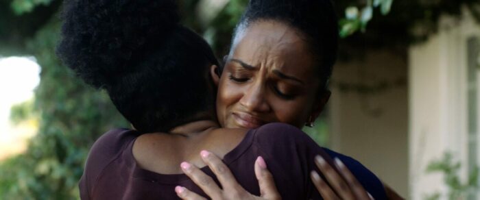 A woman hugs a friend while nearly crying.