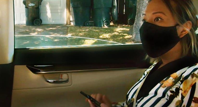 Arlene Barshinger wearing a black mask rides in a car driving through Los Angeles