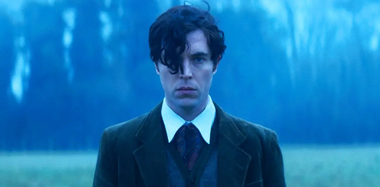 Tom Hughes as Robert Graves stares ahead while standing in the rain