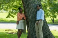 Michelle and Barack share a conversation leaning against a tree.