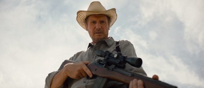 Liam Neeson as Jim, holding a rifle and staring at the ground