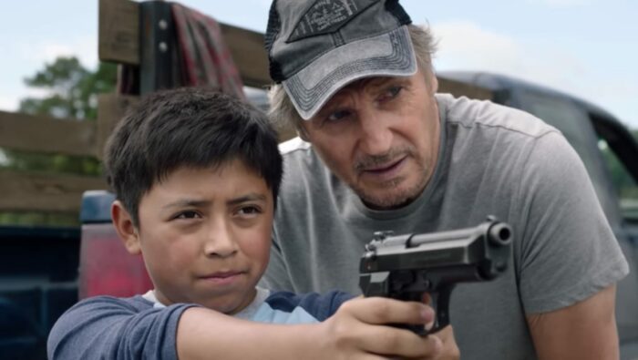 Miguel points a gun at the horizon with Jim looking on, guiding him