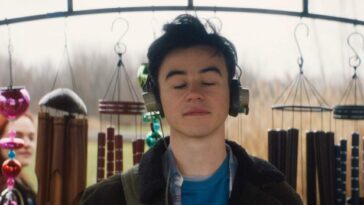 Marcus closes his eyes to listens to windchimes through his headphones
