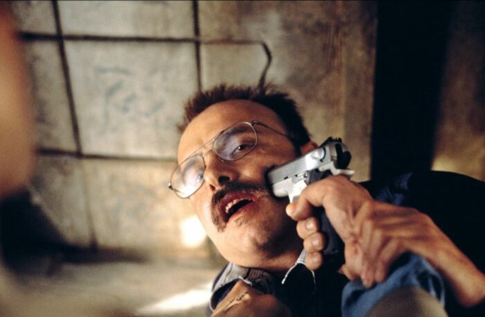 Leonard puts a gun in Teddy's (Joe Napolitano) face.