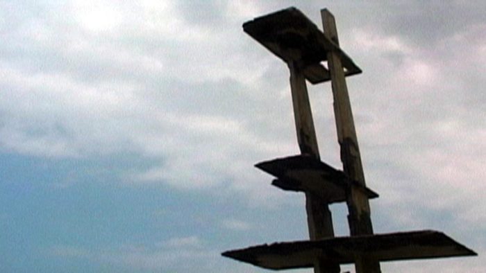 Still from Drexciya on Criterion Channel. A rotting diving board is framed against a blue sky.
