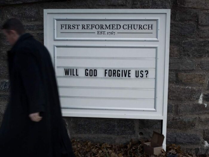 Toller walks away from the church's sign. It says "WILL GOD FORGIVE US?"