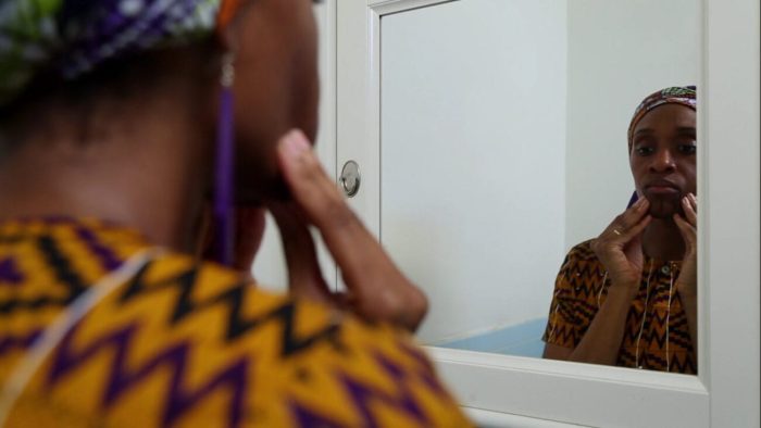 Still from On Monday Last Week. Actress Chinasa Ogbuagu stands in front of a mirror. She is touching her face.