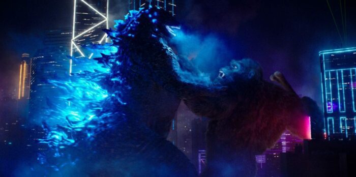 Godzilla and Kong brawl in at night in a city.