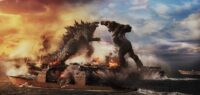 Kong swings a punch towards Godzilla while the two stand on an aircraft carrier.