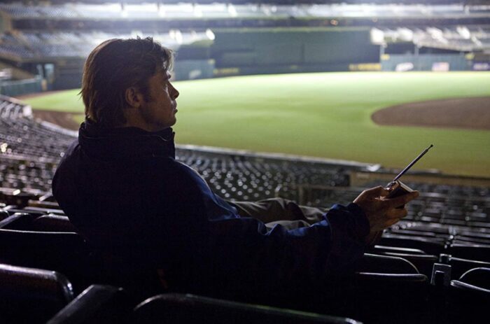Billy sits in an empty stadium listening to a radio.