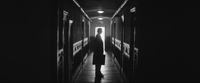 Criterion Channel Shorts March. Still from Man Rots from the Head. Michael Cera stands silhouetted in a hallway. The shot is in black and white.