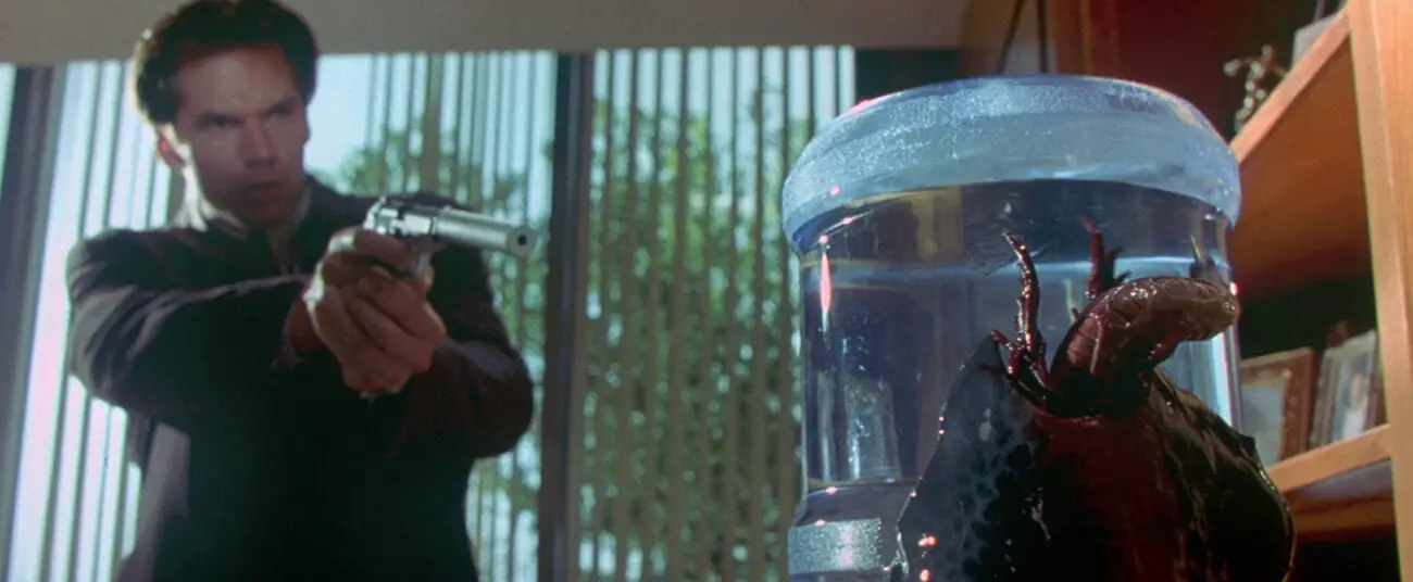 Sam Nivens points a gun at an alien on a water cooler