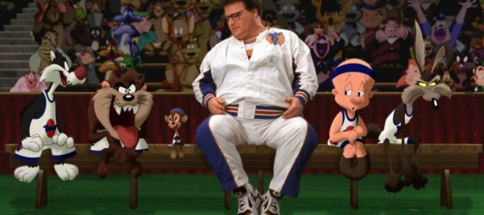 Wayne Knights sits in the middle of several Looney Tunes characters during the basketball game. They are all wearing uniforms