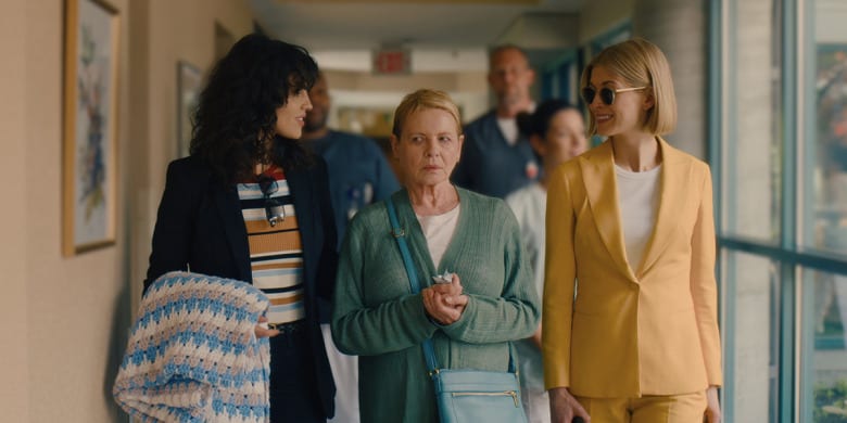 Marla and her girlfriend Fran walk an uneasy looking Jennifer Peterson down the hallway of the retirement facility she's been coerced into living at. 