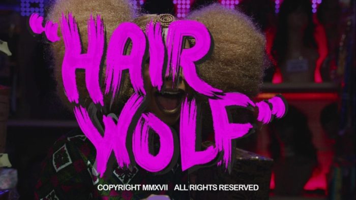 Title card from Hair Wolf. The words "Hair Wolf" are overlayed over a screaming woman. The words are bright pink and look like they were written in finger paints.