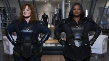 Lydia and Emily suit up and put their fists on their hips.
