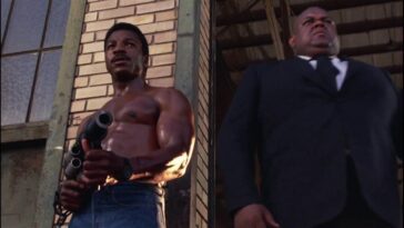 Action Jackson standing shirtless holding a weapon