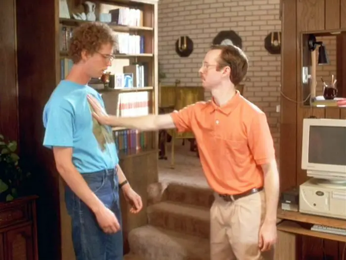 Kip (Aaron Ruell) shoving Napoleon (Jon Heder) at the bottom of their carpeted three-stair descent into their living room. Neither of them appear very emotive.