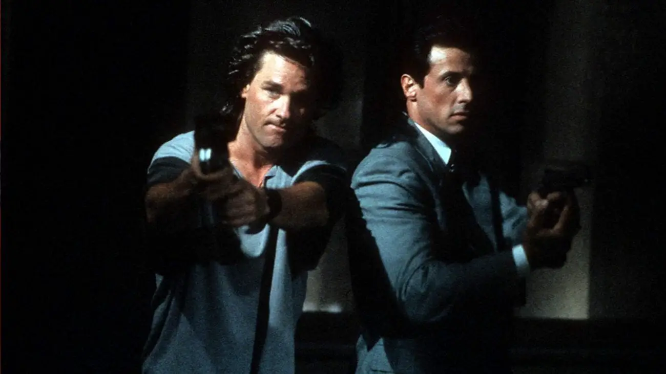 Tango and Cash standing together with guns drawn