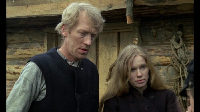 The characters Karl Oscar and Kristina stand in front of their log home and bid farewell to younger brother Robert.