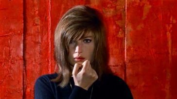 Monica Vitti with a hand to her face in front of a red background