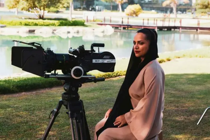 Nayla Al Khaja aits behind a camera on the grass while preparing a film shot