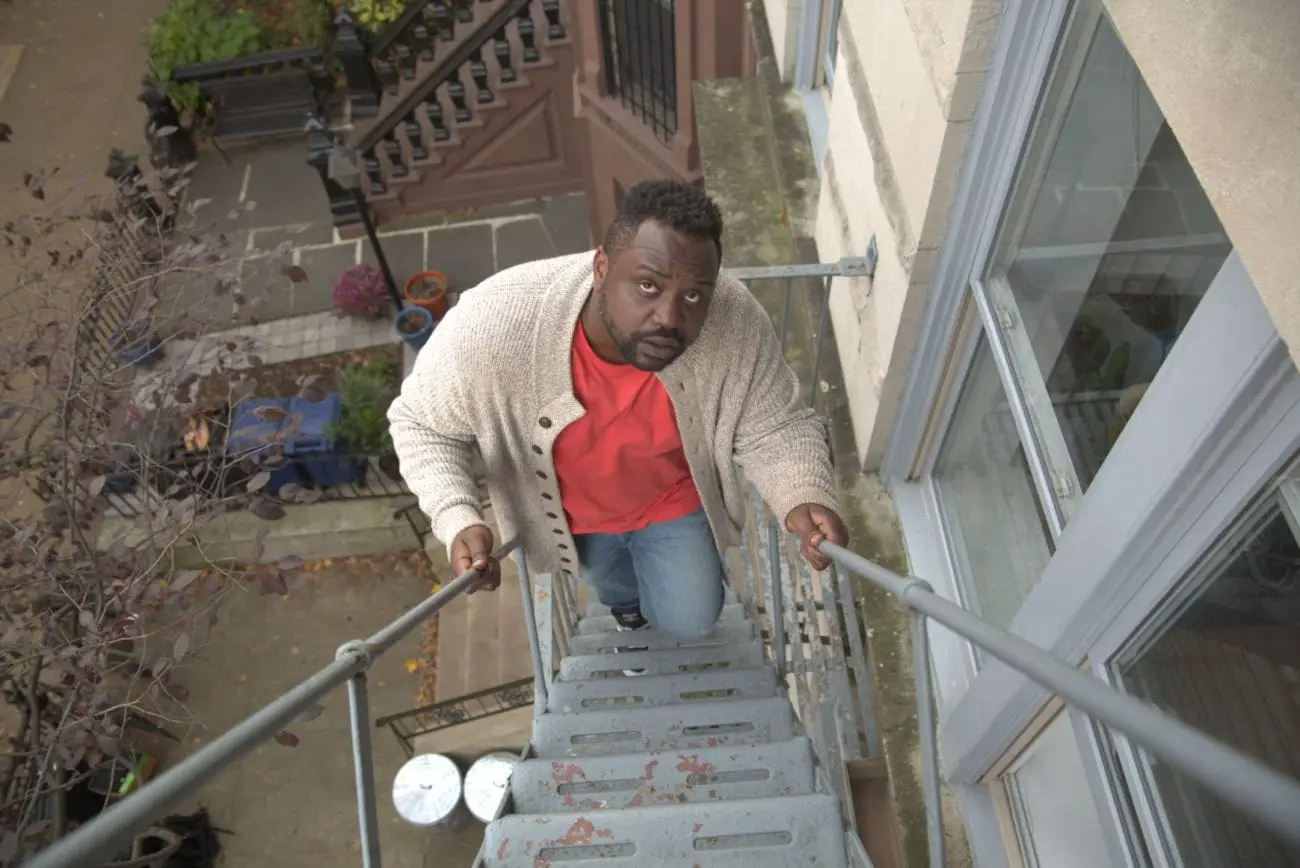 Charles looks up while walking up a fire escape.