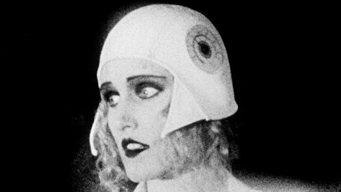 Still from Heart of the World. Anna, the state scientist, looks distressed. The shot is in black-and-white, and Anna is made up to look like a silent film actress.