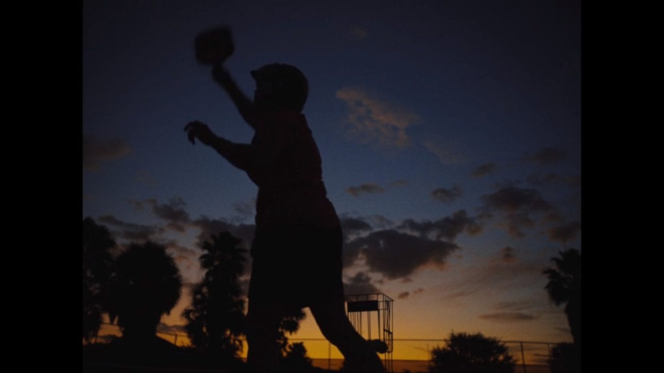 A woman in silhoutte practices pickleball at dusk.
