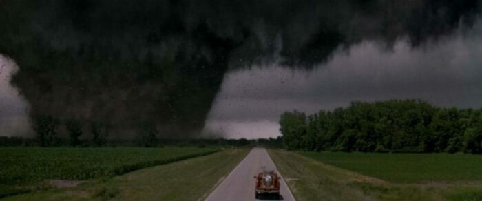 A pickup trick nears the path of an F5 tornado near a road.
