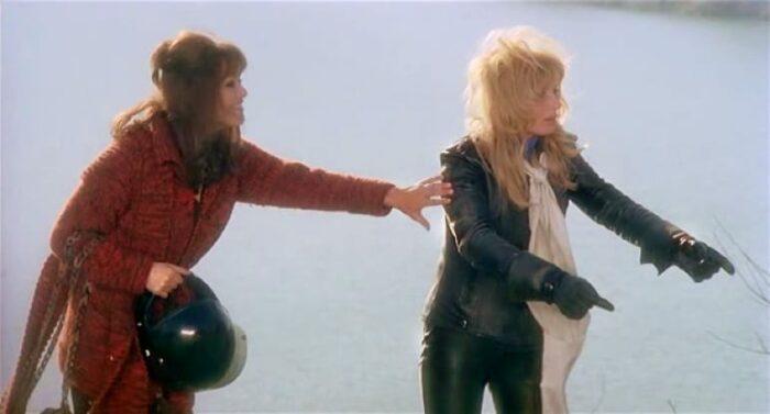 A woman in a red wool coat attempts to calm a blonde in black leather