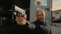 H (Jason Statham) points a gun at the men who are trying to rob his cash truck.