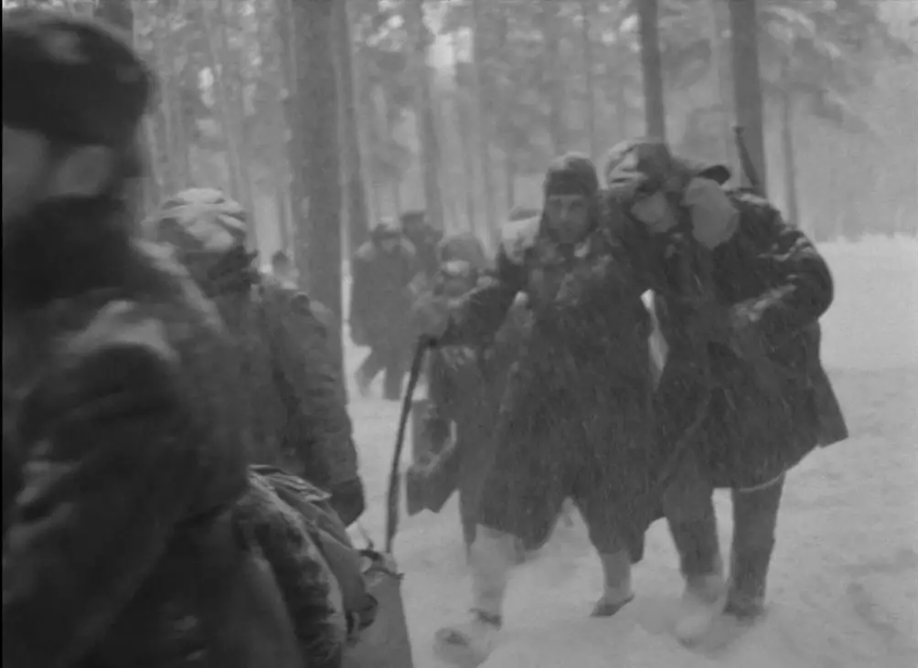 A wounded group of soldiers and villagers are shown in the snowy woods in this image from The Ascent