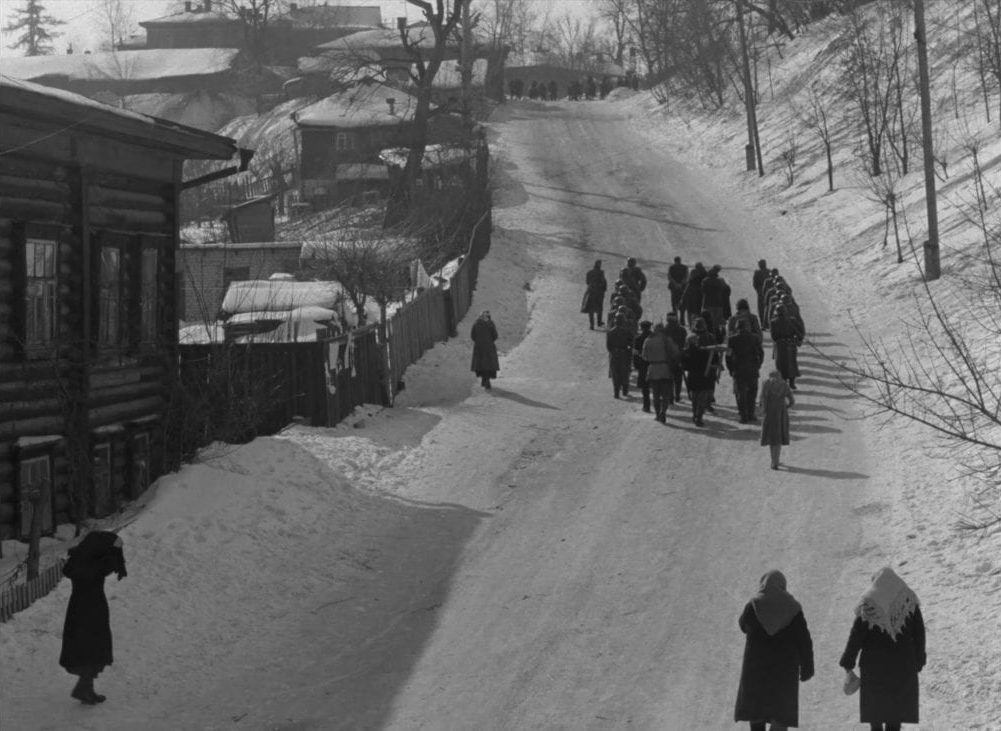 A small group of captive villagers are led up a snowy hill by German soldiers in this image from The Ascent.