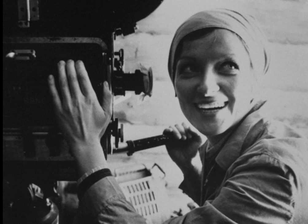 Larisa Shepitko is depicted smiling as she operates a film camera.