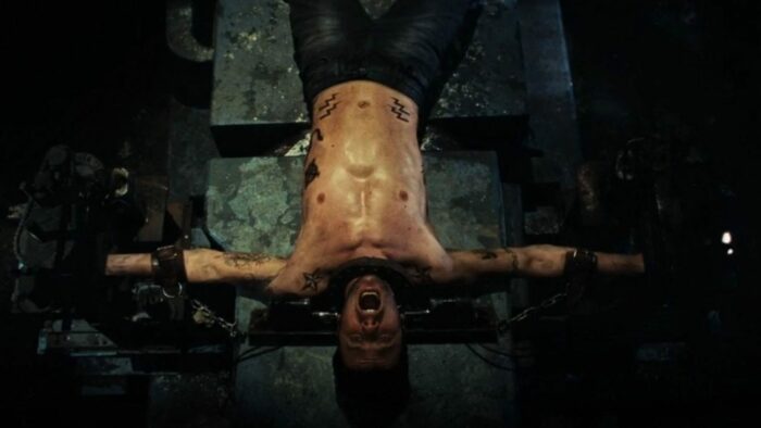 A man is tied down to a table as a pendulum swings above