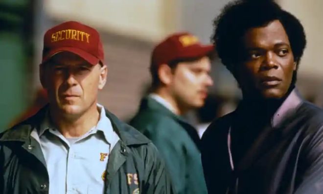 Elijah Price (Samuel L. Jackson) observes David Dunn (Bruce Willis) as he works as a security guard at a football stadium.