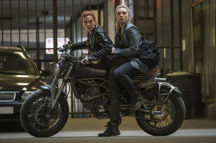 Yelena and Natasha stop after a turn on a motorcycle.