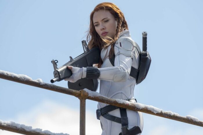Natasha aims her rifle down as pursuing guards.