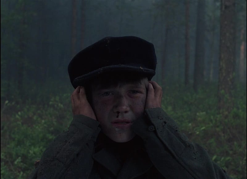 In this image from Come and See, the character Flyora is depicted holding his hands to his ears after a German attack leaves him partially deaf.