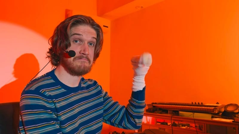 In this image from Inside, Bo Burnham is depicted holding a sockpuppet in front of an orange background.