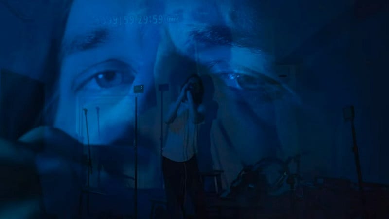 In this image from Inside, a triple exposure of Bo Burnham depicts multiple blue-tinted images of the singer performing "Goodbye".