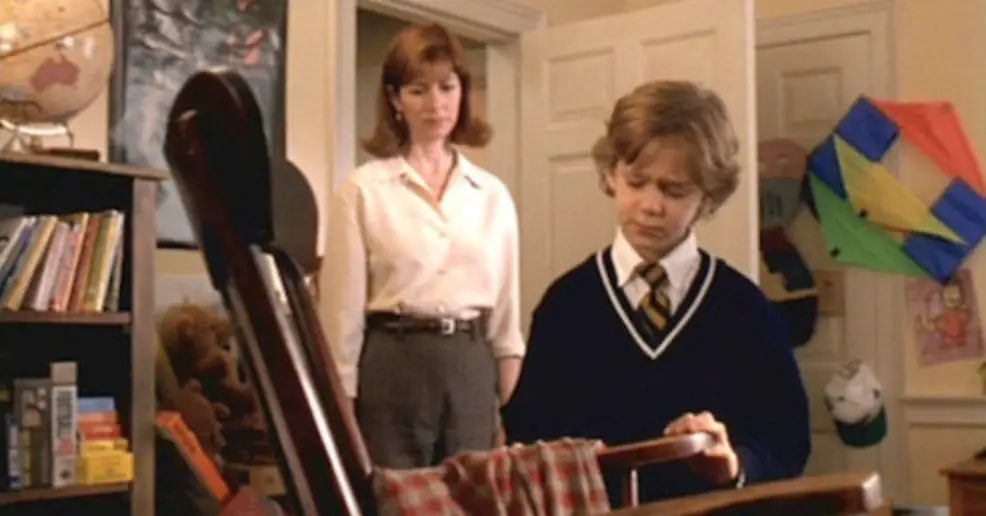 Joshua (Joseph Cross) mourns the death of his grandfather while looking at his old rocking chair with his mother (Dana Delany) looking on.