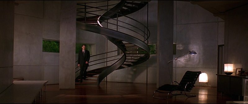 In this image from Gattaca, the character Vincent (Hawke) is depicted in an extreme long shot descending a spiral staircase in an architecturally modern home.