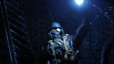 Explorer in a gas mask holds a light up in the dark